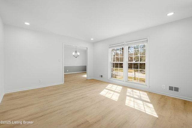 empty room with visible vents, recessed lighting, light wood-type flooring, and an inviting chandelier