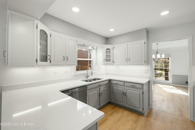 kitchen with stainless steel dishwasher, gray cabinetry, light wood-style floors, and a sink