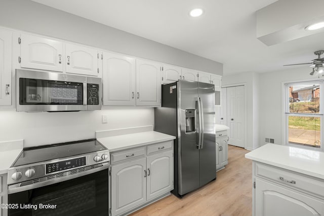 kitchen with light wood finished floors, white cabinets, stainless steel appliances, and light countertops