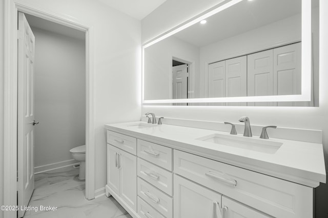 bathroom with a sink, toilet, marble finish floor, and double vanity