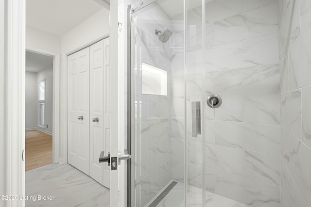 bathroom with a shower stall and marble finish floor