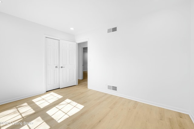 unfurnished bedroom with visible vents, baseboards, a closet, and wood finished floors