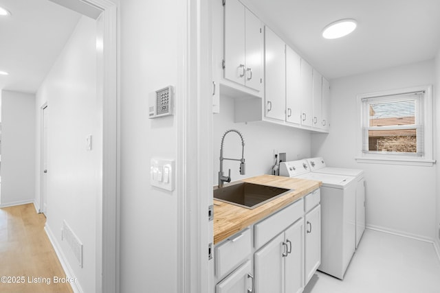 laundry room with visible vents, a sink, washer and dryer, cabinet space, and baseboards