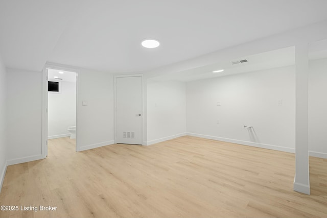 finished below grade area with visible vents, baseboards, and light wood-style flooring