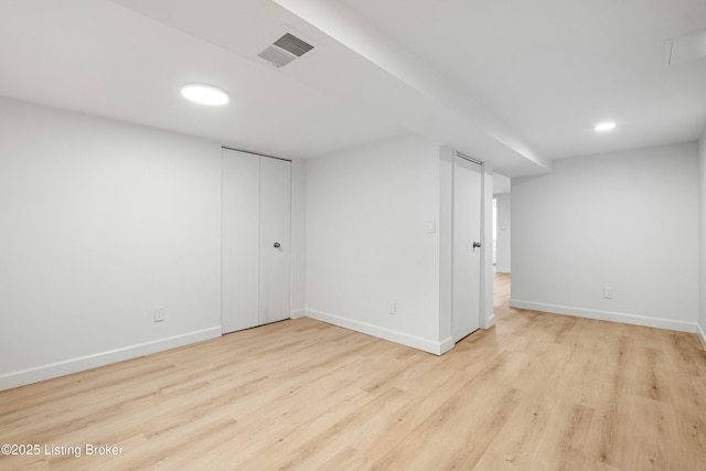 spare room with wood finished floors, visible vents, and baseboards