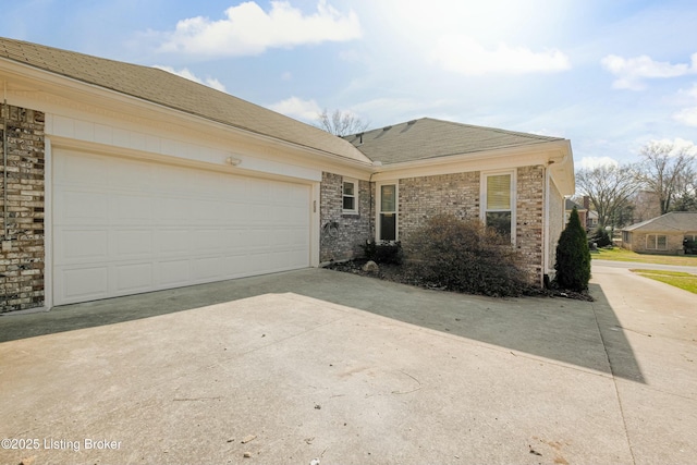 single story home featuring brick siding, an attached garage, driveway, and a shingled roof