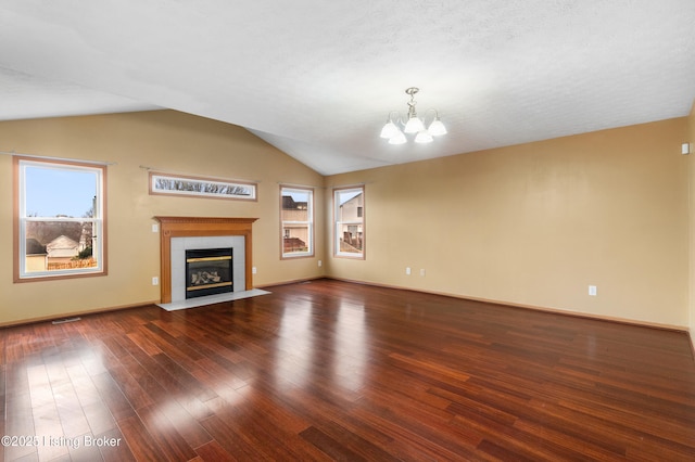 unfurnished living room featuring wood finished floors, visible vents, lofted ceiling, a fireplace, and a notable chandelier