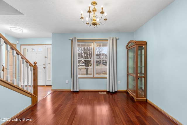 interior space with visible vents, wood finished floors, baseboards, a chandelier, and stairs