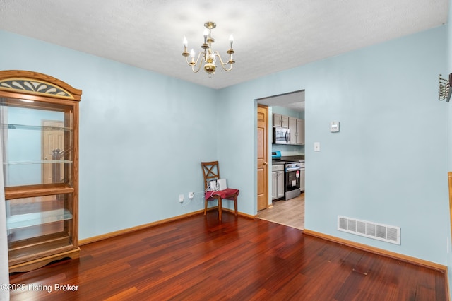 unfurnished room featuring a chandelier, visible vents, light wood-type flooring, and baseboards