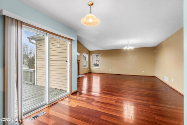 spare room with a chandelier, visible vents, lofted ceiling, and wood finished floors