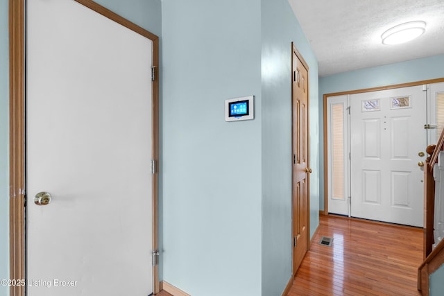 entrance foyer featuring light wood-style flooring, visible vents, and a textured ceiling