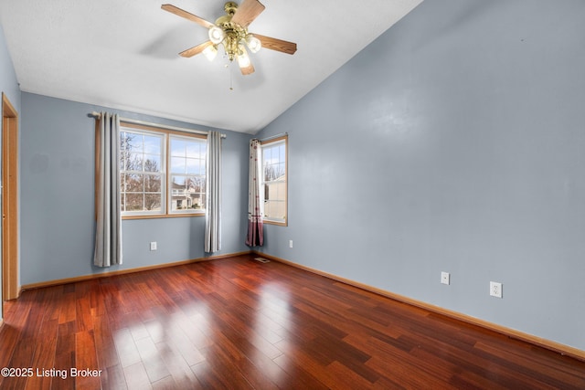 spare room with vaulted ceiling, wood finished floors, baseboards, and ceiling fan