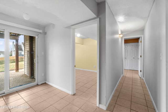 hall featuring light tile patterned floors and baseboards