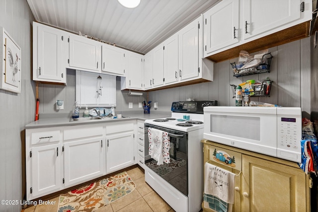 kitchen featuring light countertops, light tile patterned flooring, white microwave, and range with electric cooktop