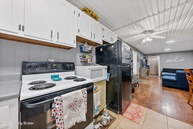 kitchen featuring white microwave, light tile patterned floors, freestanding refrigerator, electric range, and white cabinets