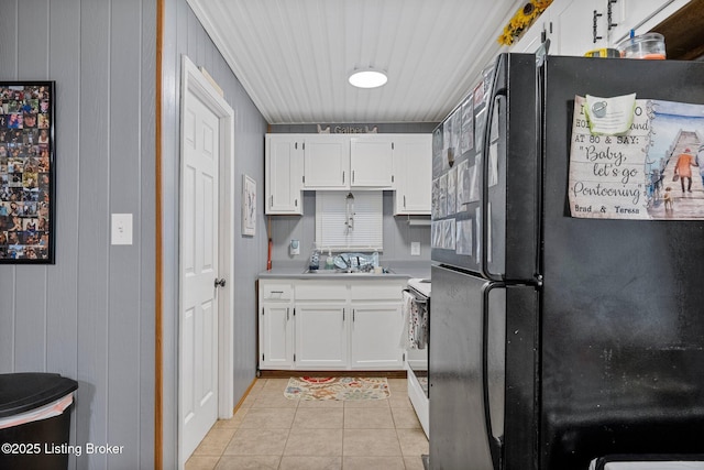 kitchen with light tile patterned floors, freestanding refrigerator, light countertops, white cabinets, and white electric range