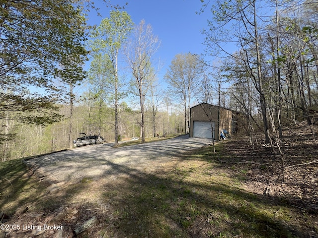 view of yard with a garage, dirt driveway, and an outbuilding