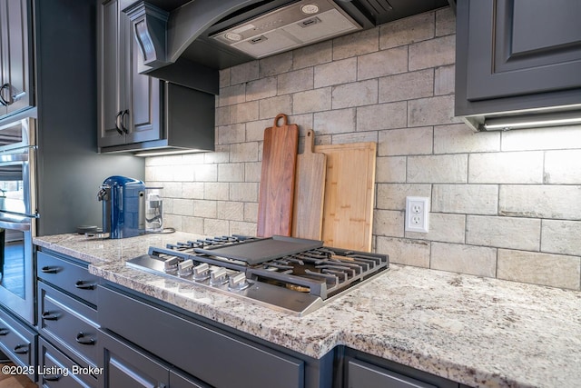 kitchen with light stone counters, decorative backsplash, stainless steel appliances, and extractor fan