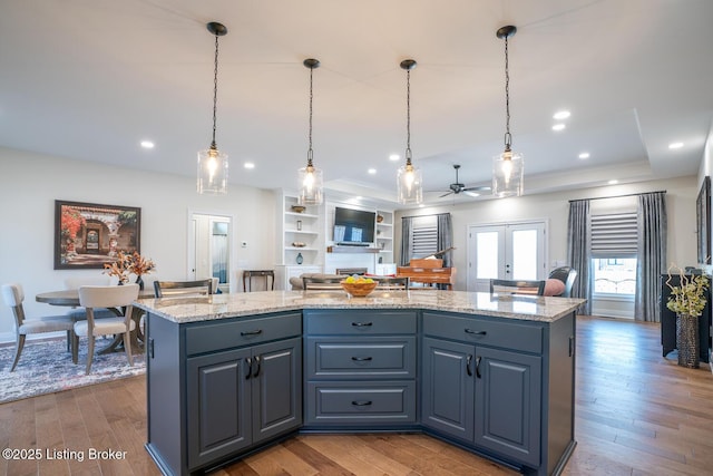 kitchen featuring a kitchen island, light stone countertops, hardwood / wood-style floors, recessed lighting, and french doors