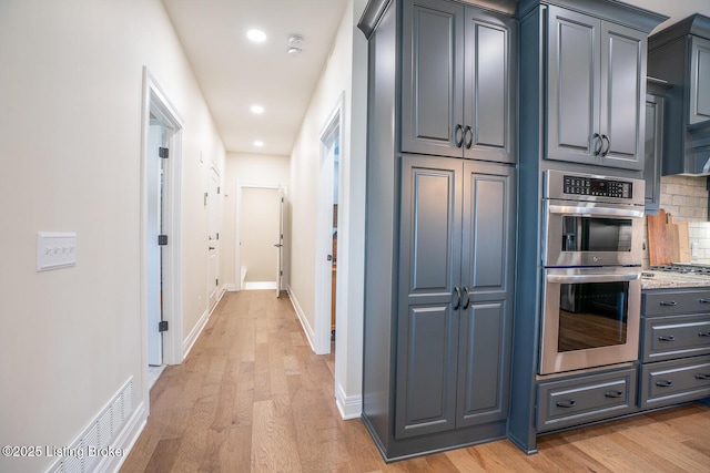 kitchen featuring tasteful backsplash, gray cabinetry, baseboards, light wood-style flooring, and stainless steel appliances