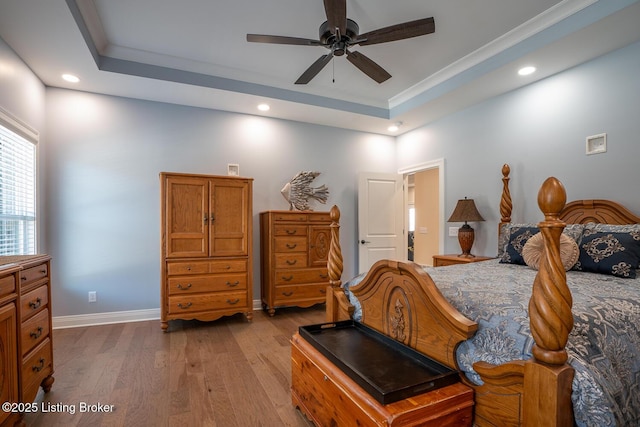 bedroom featuring recessed lighting, baseboards, a tray ceiling, and wood finished floors