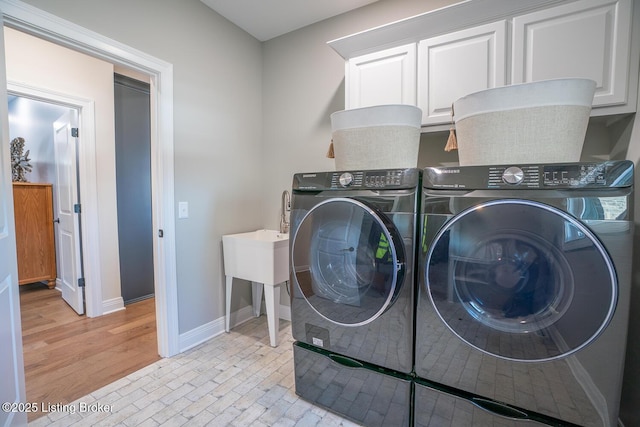 laundry area with cabinet space, washer and dryer, brick floor, and baseboards