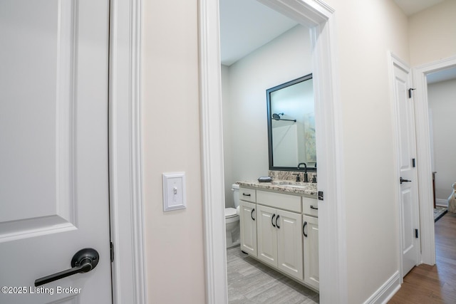 bathroom featuring toilet, vanity, and wood finished floors