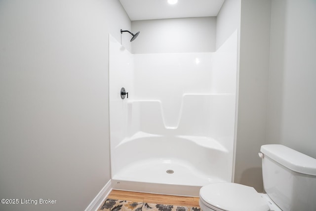 full bath featuring wood finished floors, toilet, a shower, and baseboards