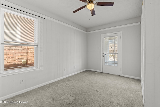 carpeted spare room featuring baseboards and a ceiling fan