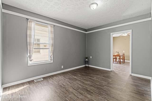 empty room with visible vents, dark wood-type flooring, a textured ceiling, baseboards, and ceiling fan