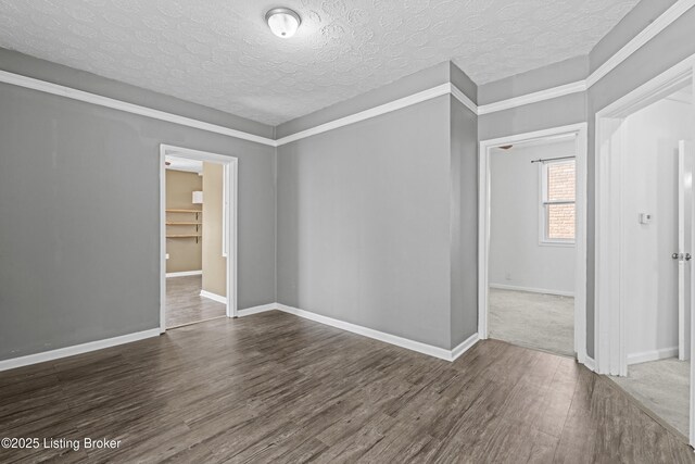 empty room with wood finished floors, baseboards, and a textured ceiling