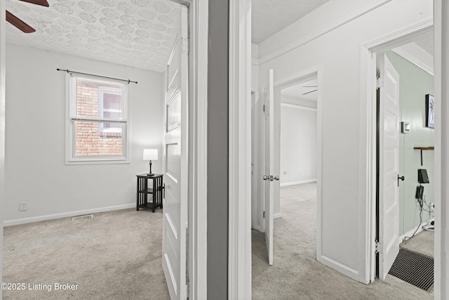 hall featuring a textured ceiling, baseboards, and carpet floors