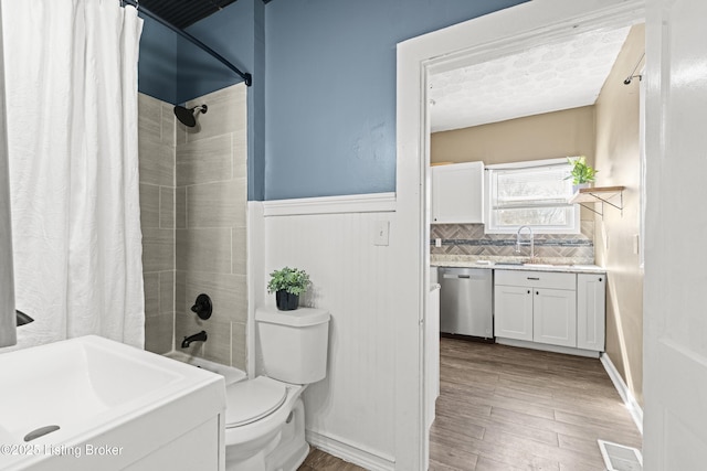 bathroom featuring visible vents, shower / bath combo with shower curtain, toilet, wainscoting, and vanity