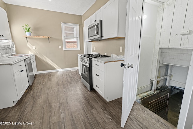 kitchen featuring a sink, open shelves, dark wood-style floors, appliances with stainless steel finishes, and white cabinets