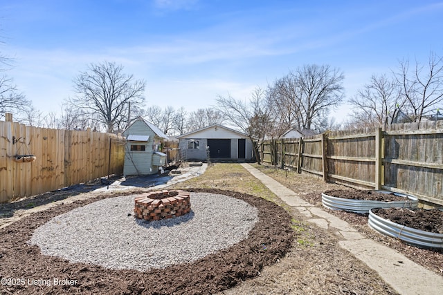 view of yard with a fenced backyard, an outdoor fire pit, and an outdoor structure