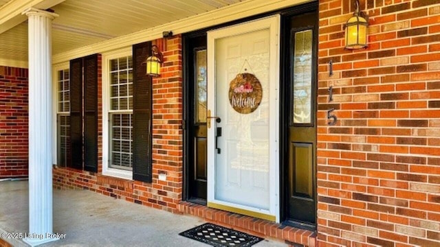 view of exterior entry with brick siding and covered porch