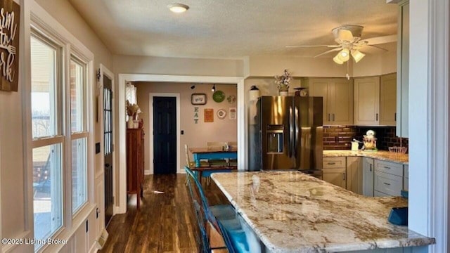 kitchen featuring tasteful backsplash, light stone countertops, dark wood-style floors, stainless steel fridge, and a ceiling fan