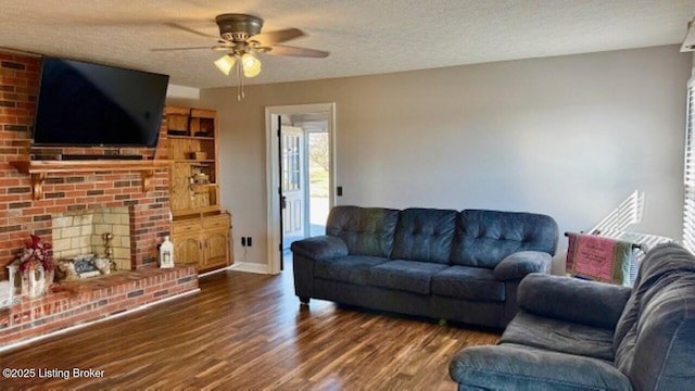 living room featuring ceiling fan, a textured ceiling, wood finished floors, and a fireplace