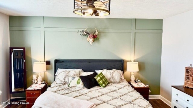 bedroom featuring dark wood-style floors and a decorative wall