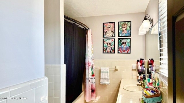 full bath featuring a wainscoted wall, curtained shower, tile walls, and vanity