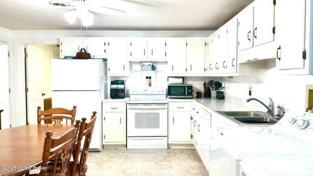 kitchen with a sink, washing machine and dryer, white appliances, white cabinets, and light countertops