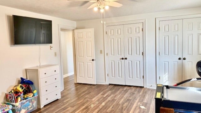 bedroom featuring wood finished floors, baseboards, two closets, and ceiling fan