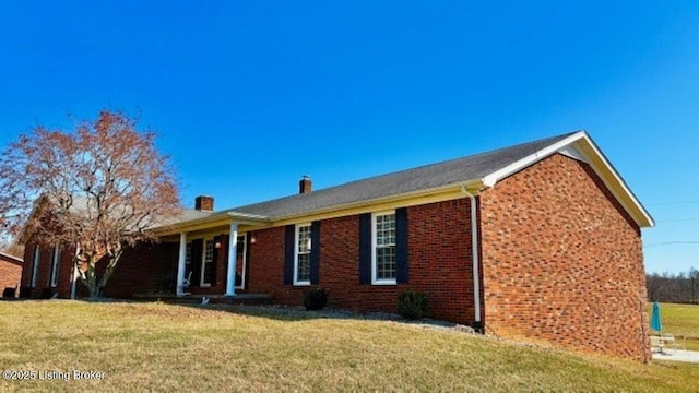 view of front of house with brick siding, a chimney, and a front lawn