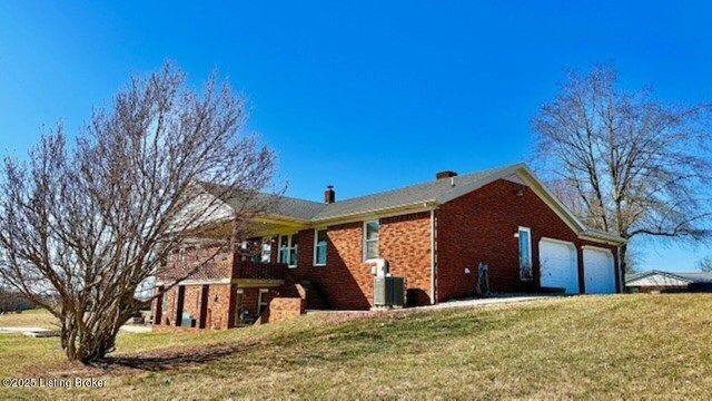 view of side of home with brick siding, a lawn, and an attached garage