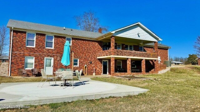 rear view of property featuring a patio area, a lawn, central AC, and brick siding