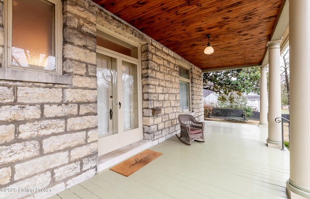 entrance to property with a porch and stone siding