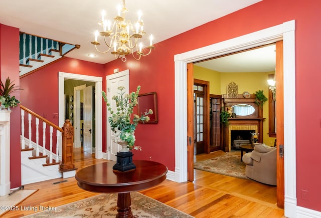 foyer entrance featuring visible vents, wood finished floors, a fireplace, baseboards, and stairs