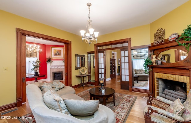 living area with wood finished floors, a fireplace, visible vents, and a chandelier