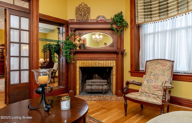 living area featuring baseboards, a brick fireplace, and wood finished floors