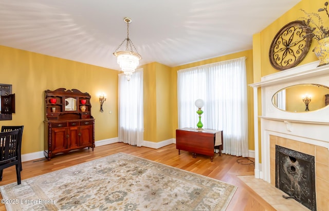 sitting room with a fireplace, wood finished floors, baseboards, and a chandelier